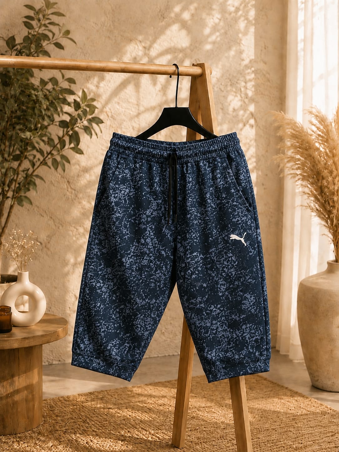 Dark navy blue printed men’s shorts with a comfortable elastic waistband, adjustable drawstring, side pockets, and relaxed fit, displayed on a wooden clothing rack.